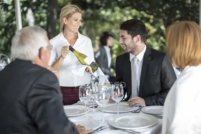 focused_181534190-Waitress-showing-white-wine-clients