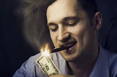Man lighting his cigar with 100 dollars note